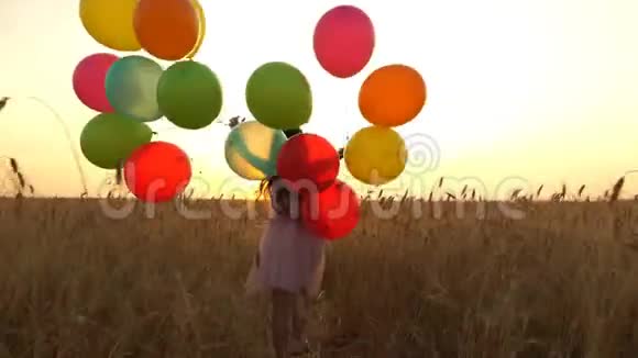 穿着五颜六色的气球的小女孩正跑过田野视频的预览图
