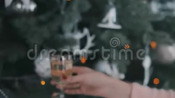 穿着毛衣的女孩在圣诞树附近喝着香槟视频的预览图