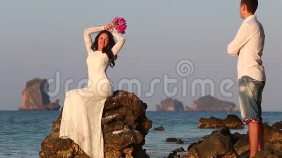 新娘坐在岩石上摆出新郎看日出的姿势视频的预览图
