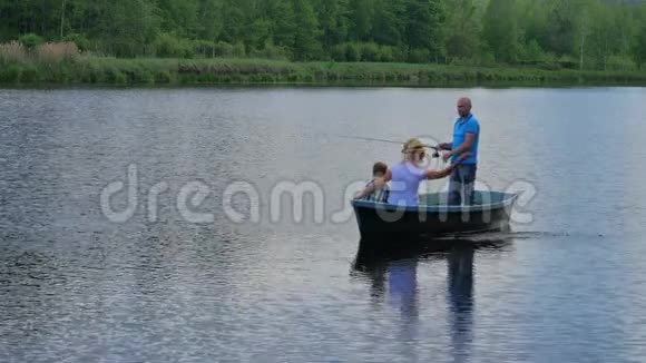 妈妈爸爸和小儿子在湖边的小船上放松视频的预览图