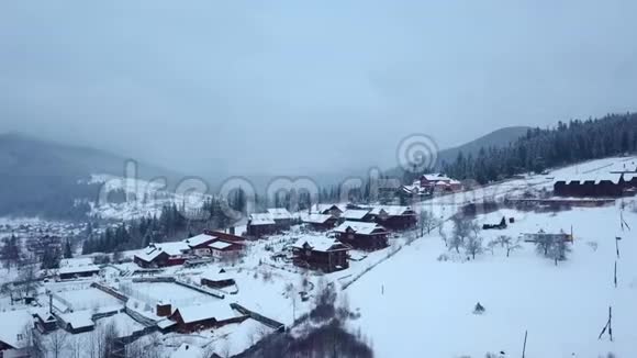 冬季山区有人居住地区的空中活动雪山山坡上的村庄建筑和房屋视频的预览图