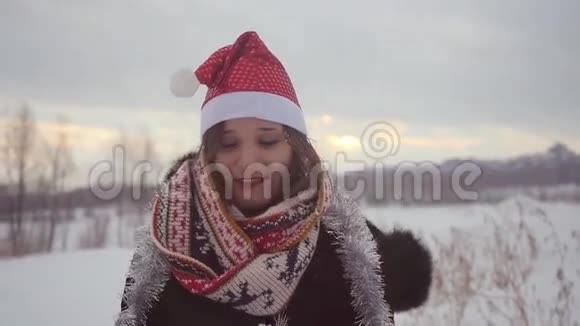 快乐的年轻女子戴着圣诞帽在户外玩得很开心冬天下雪自然是慢动作的视频的预览图