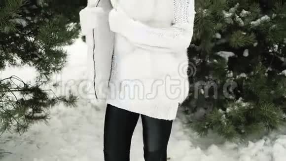 美丽的年轻女子在一棵雪白的松树上摆姿势穿着白色的连衣裙视频的预览图