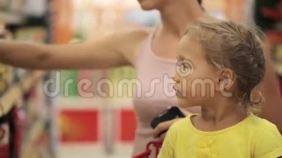 妈妈和小女儿在超市的糖果区选择零食视频的预览图