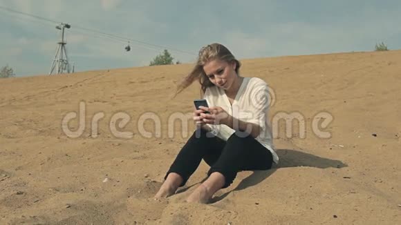 美丽的女孩坐在沙滩上靠在沙滩上视频的预览图