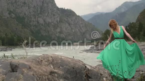 年轻的女人穿着一件长长的流动的衣服在河山的背景上给一个在绿色中盘旋的女人上色视频的预览图