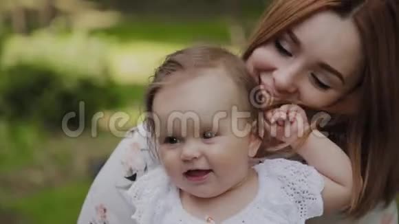 美丽快乐的年轻母亲把女儿抱在公园里视频的预览图