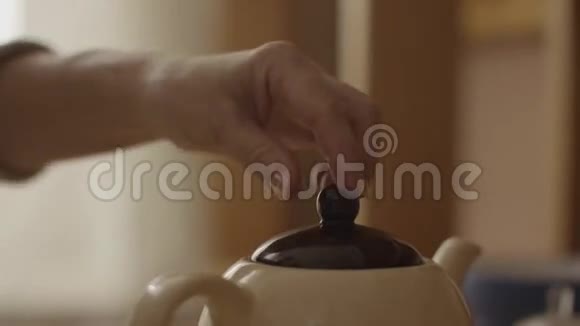 女人把沸水倒进杯子里用茶袋泡茶女人用茶把热水倒进茶壶里视频的预览图