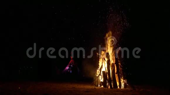 一个巨大的篝火在沙子和伟大的wigwam小屋的背景很多火花视频的预览图