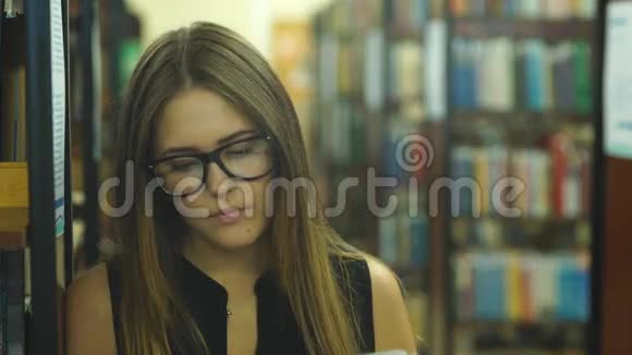 女学生以书架为背景阅读图书馆书籍视频的预览图