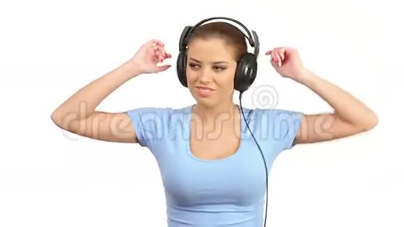 一位年轻的美女在听大型立体声耳机音乐视频的预览图