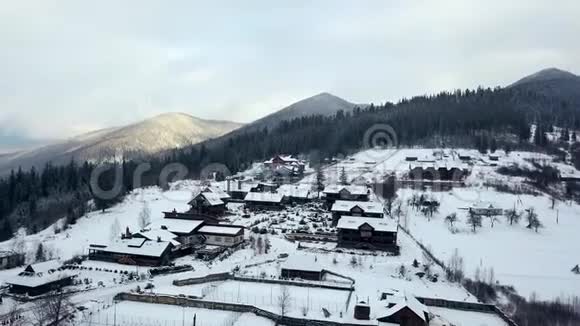 冬季山区有人居住地区的空中活动雪山山坡上的村庄建筑和房屋视频的预览图