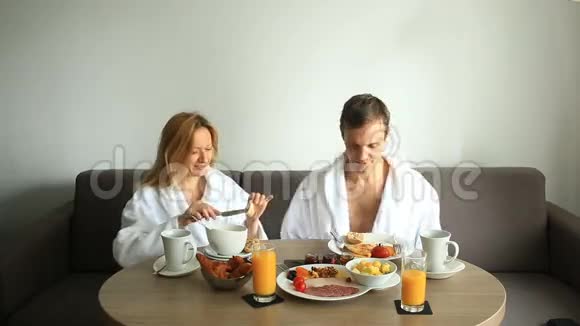 年轻夫妇在酒店房间的沙发上吃早餐视频的预览图