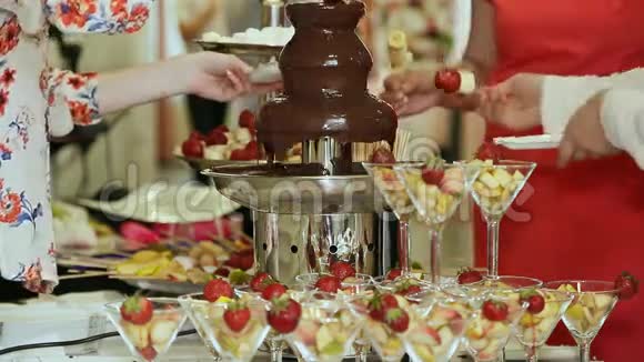 人们把草莓浸在巧克力喷泉里庆祝活动视频的预览图