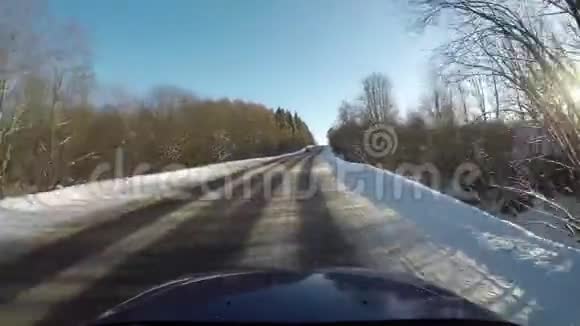 冬天开车在穿过森林的路上在晴朗的一天大角度拍摄视频的预览图