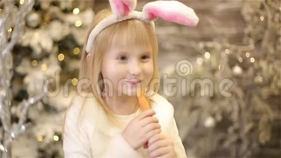 穿着兔子白色服装的小女孩在圣诞装饰中吃胡萝卜视频的预览图