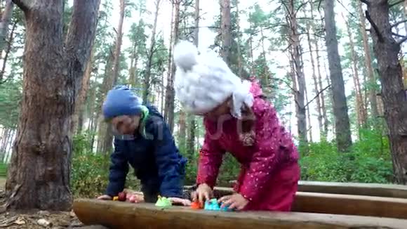 男孩和女孩玩玩具孩子们在公园的木凳上点燃他们的玩具儿童假期视频的预览图