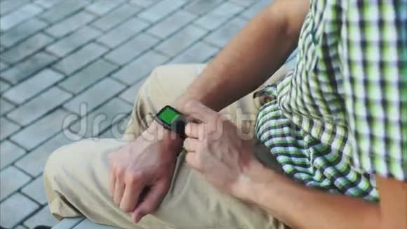 穿着休闲的男士双手使用绿色屏幕的现代智能手表视频的预览图