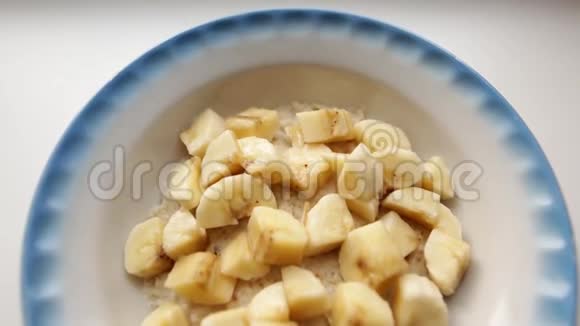 健康早餐加牛奶和香蕉的燕麦粥燕麦片在白色的面碟上装满牛奶视频的预览图