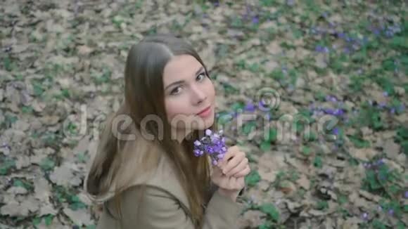 美丽的少女闻着森林里的春花视频的预览图