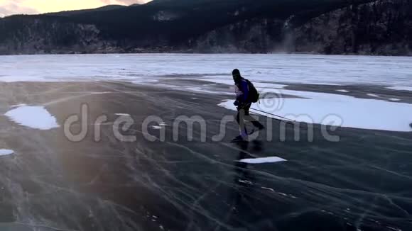 在美丽的日落中人们正在冰封的贝加尔湖上滑冰视频的预览图