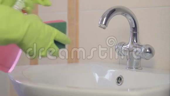 女人在家里的浴室里做家务用喷雾洗涤剂清洗水槽和水龙头序列视频的预览图