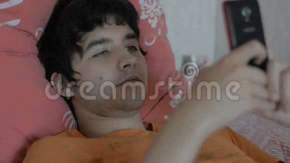 有智能手机的年轻人躺在床上视频的预览图