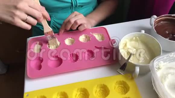 有刷子的女人用融化的白巧克力润滑硅胶做甜点视频的预览图