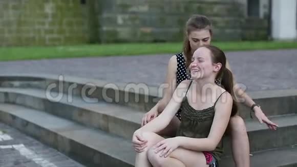 两个可爱的少女女友坐在公园的石阶上聊天视频的预览图