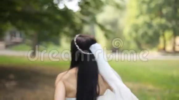 新娘穿着婚纱在微风中的草地上散步视频的预览图