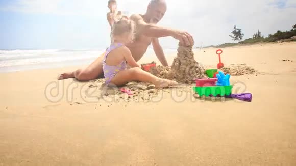 孩子们爷爷在沙滩上用海浪冲浪建造沙堡视频的预览图