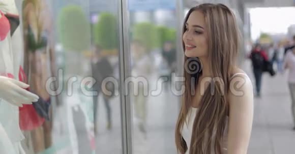 微笑的女孩看着商店的橱窗视频的预览图