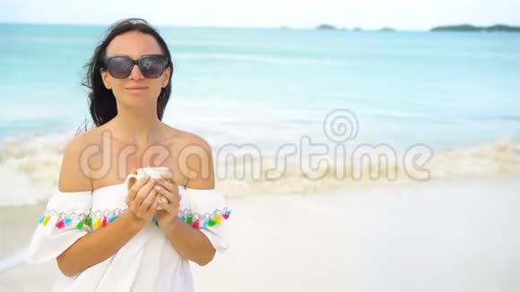 带着热咖啡的年轻女人享受海滩风景视频的预览图