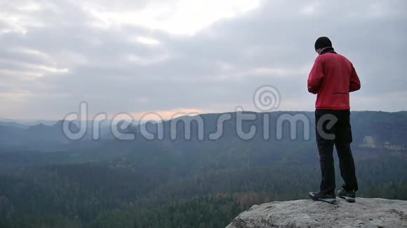 徒步旅行者穿着粉红色运动服在岩石的观点和拍摄薄雾的早晨景观在岩石里远足视频的预览图