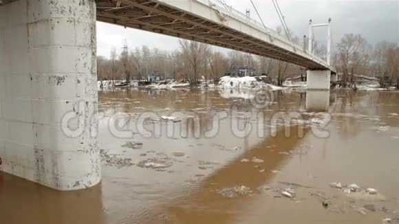 春天的河流有肮脏的棕色水和冰浮冰和桥视频的预览图