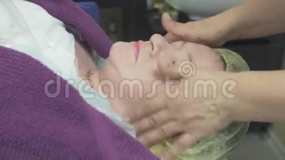 美容师在美容院给成年女性面部涂抹点润肤油视频的预览图