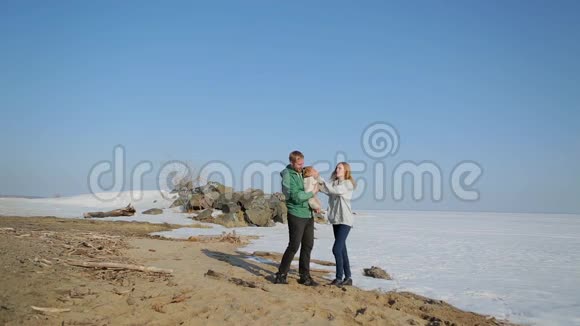 一对夫妇带着一只狗沿着冰冻的湖岸散步视频的预览图