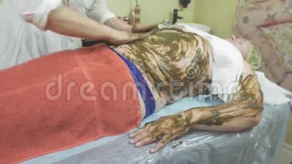 美容师在肥婆的胃上涂抹海藻混合物左手放在酒馆里视频的预览图