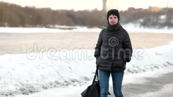 一个快乐的女孩正在冬天的公园里散步慢动作视频的预览图