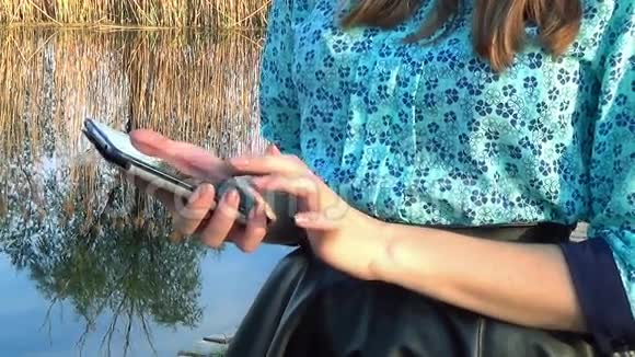 女人在河边用手机视频的预览图
