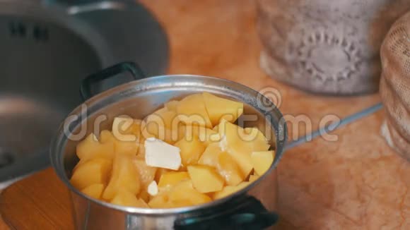 一片黄油瀑布进入土豆在一个Saucepan上的家庭厨房视频的预览图
