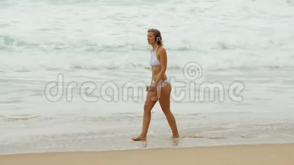 在海洋沙滩上漫步年轻女子暑假视频的预览图