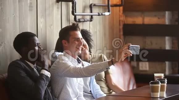 不同的快乐朋友在咖啡馆一起在智能手机上自拍视频的预览图