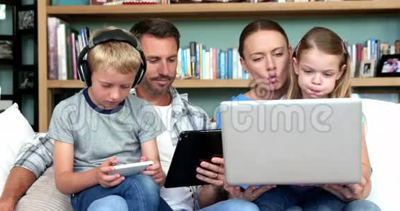可爱的家庭使用技术坐在沙发上视频的预览图