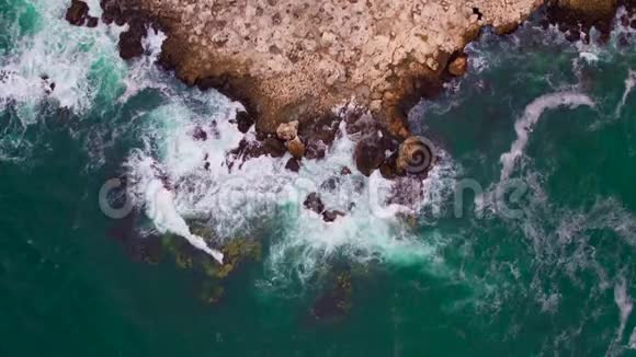 空中无人驾驶飞机俯瞰岩石海岸线海浪拍打视频的预览图