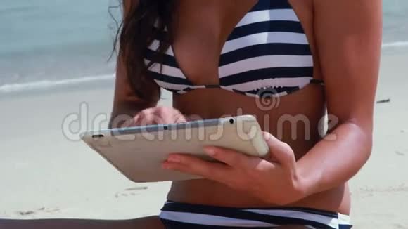 在海滩上用平板电脑接近漂亮的黑发女人视频的预览图