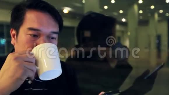 亚洲商人使用手机晚上在咖啡馆喝咖啡视频的预览图