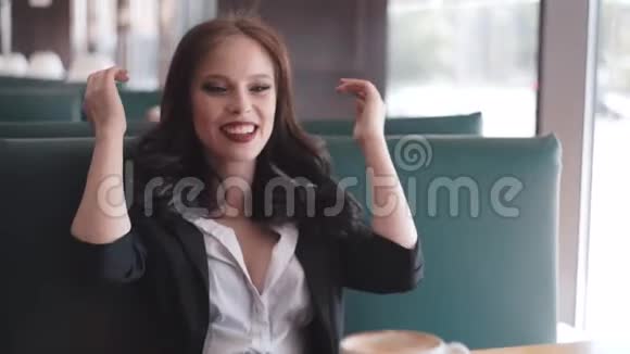 美丽的黑发女人坐在咖啡馆里调情看着镜头视频的预览图