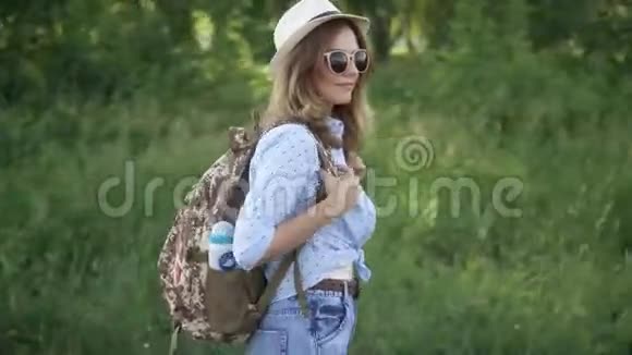 戴着帽子和太阳镜的时髦女孩的肖像带背包的年轻女子视频的预览图