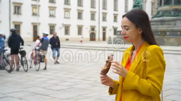 美丽的年轻女子拿着椒盐卷饼在公园放松视频的预览图